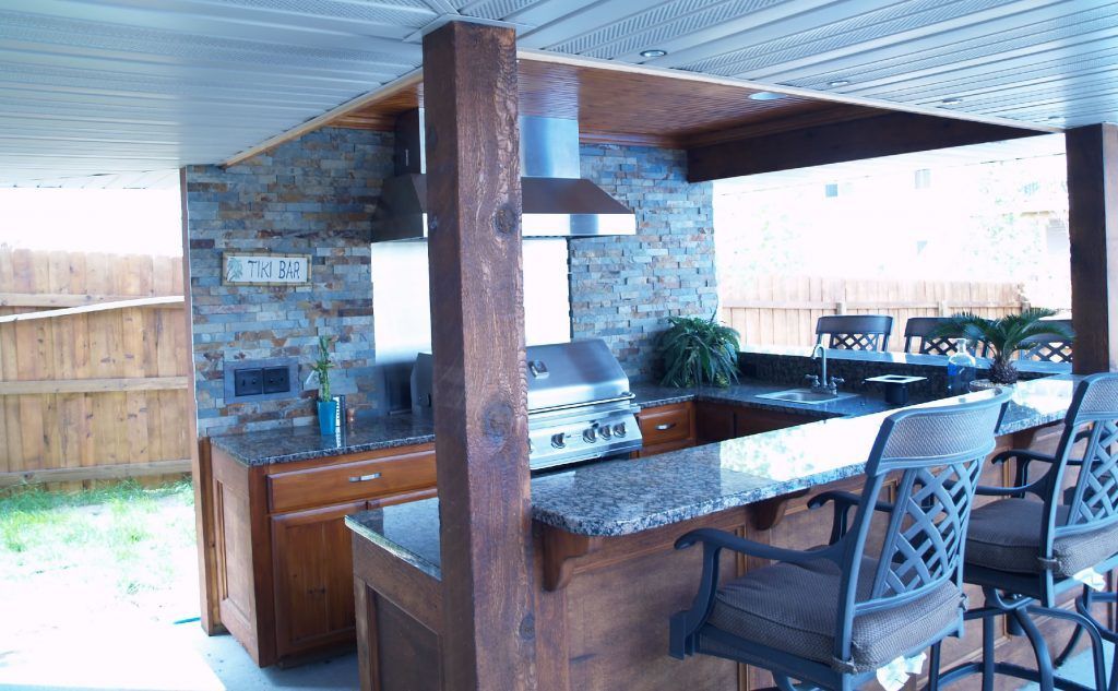 Outdoor kitchen with stone accents, granite countertop, and bar seating.