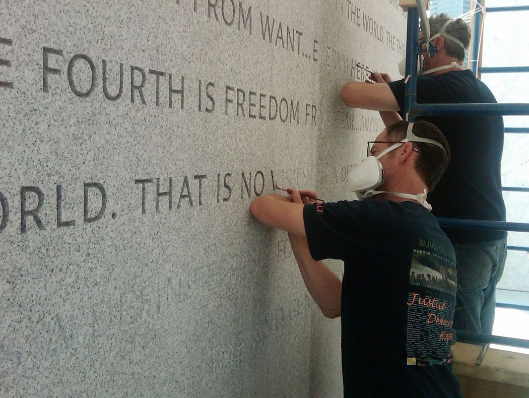 Nick Benson and Paul Russo apply a tint to the lettering at Four Freedoms Park in New York, which uses the same font planned for Peace Corps Park.