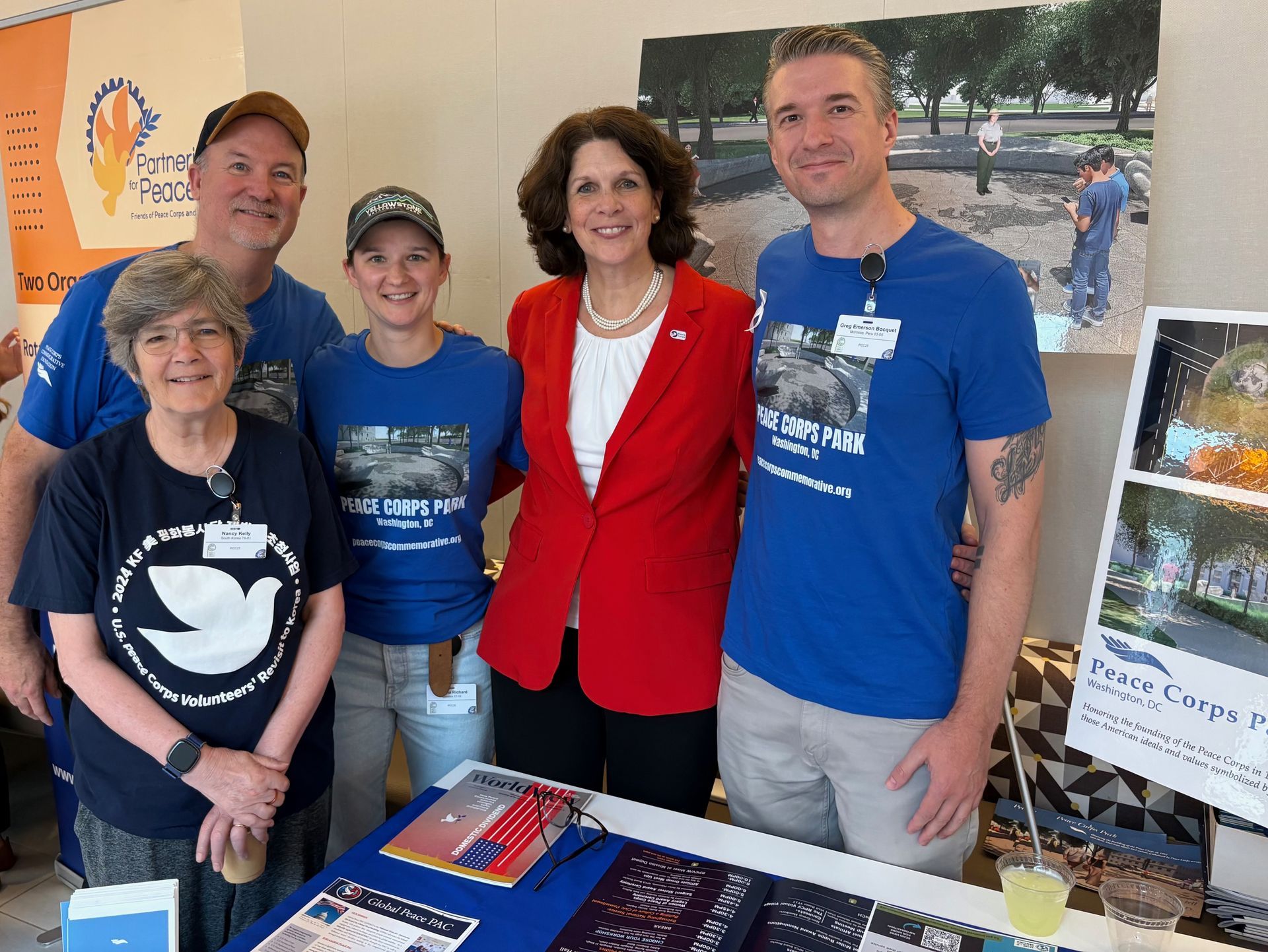 Nancy Kelly, Glenn Blumhorst, Arianna Richard, Greg Emerson welcome Dr. Allison Greene, CEO of the Peace Corps, at the Peace Corps Park exhibit table at the Peace Corps Connect conference in Washington, D.C.