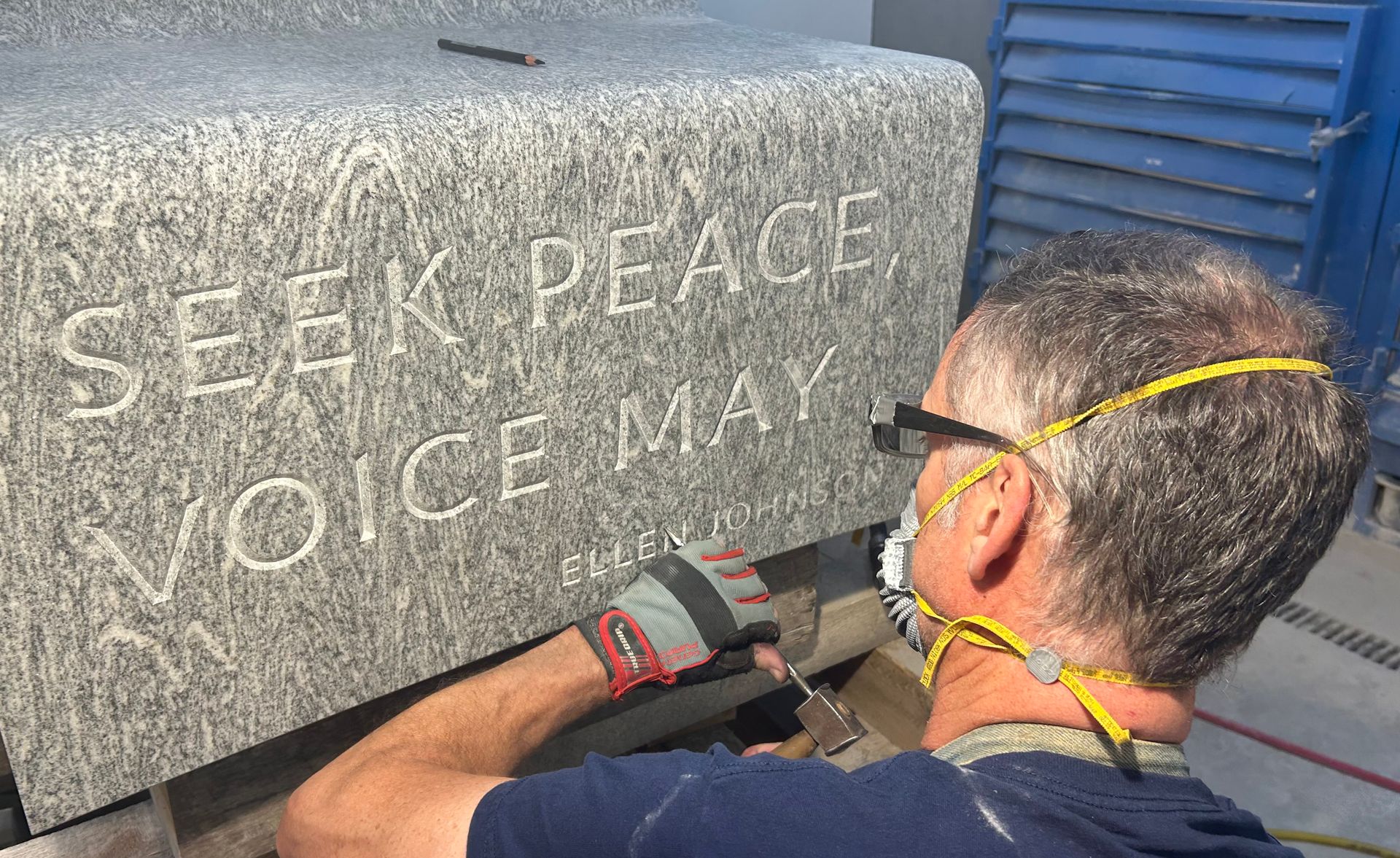 Nick Benson takes his mallet and chisel to test-carve inscriptions onto Peace Corps Park's granite bench sample