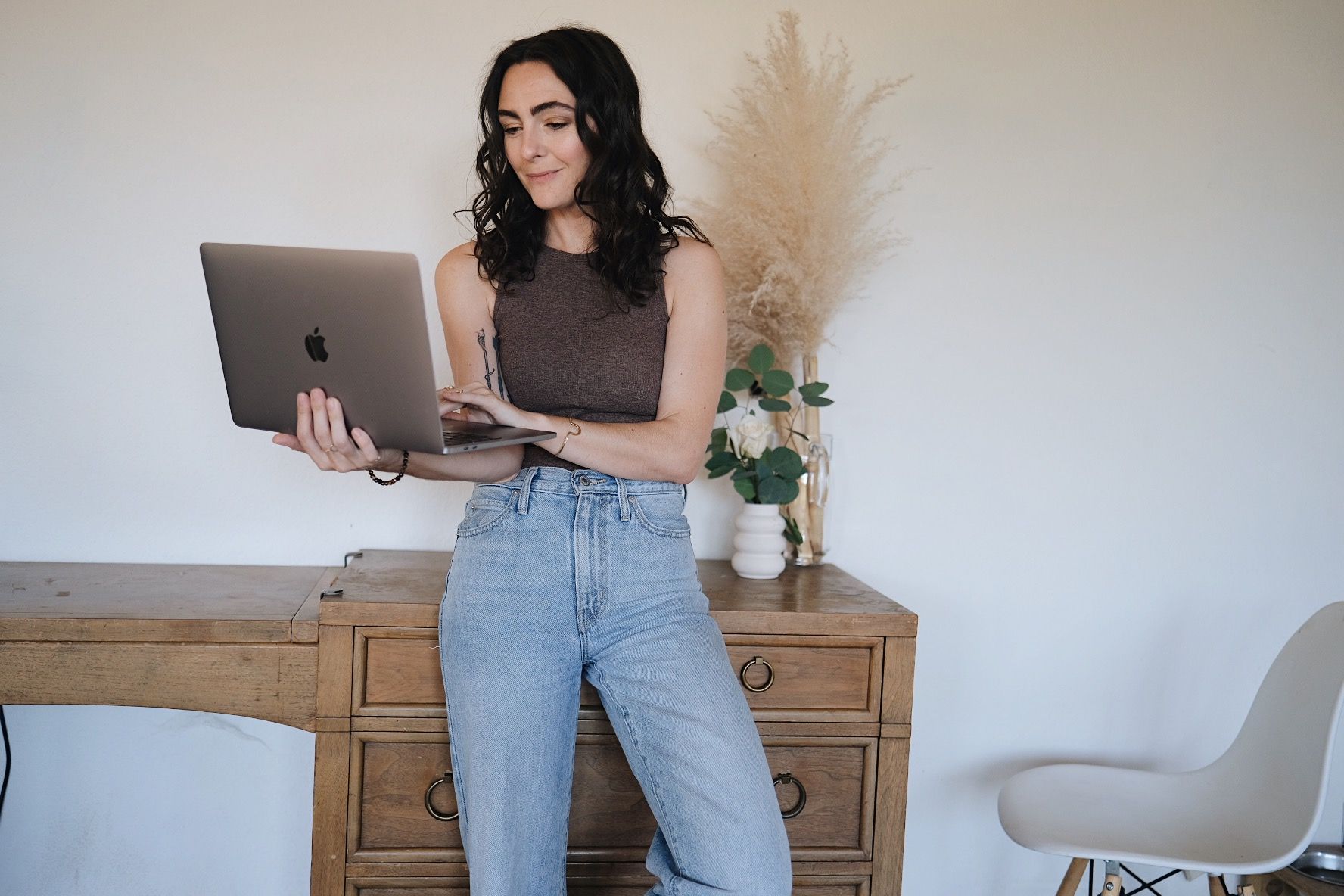 a woman is standing in front of a desk using a laptop computer .