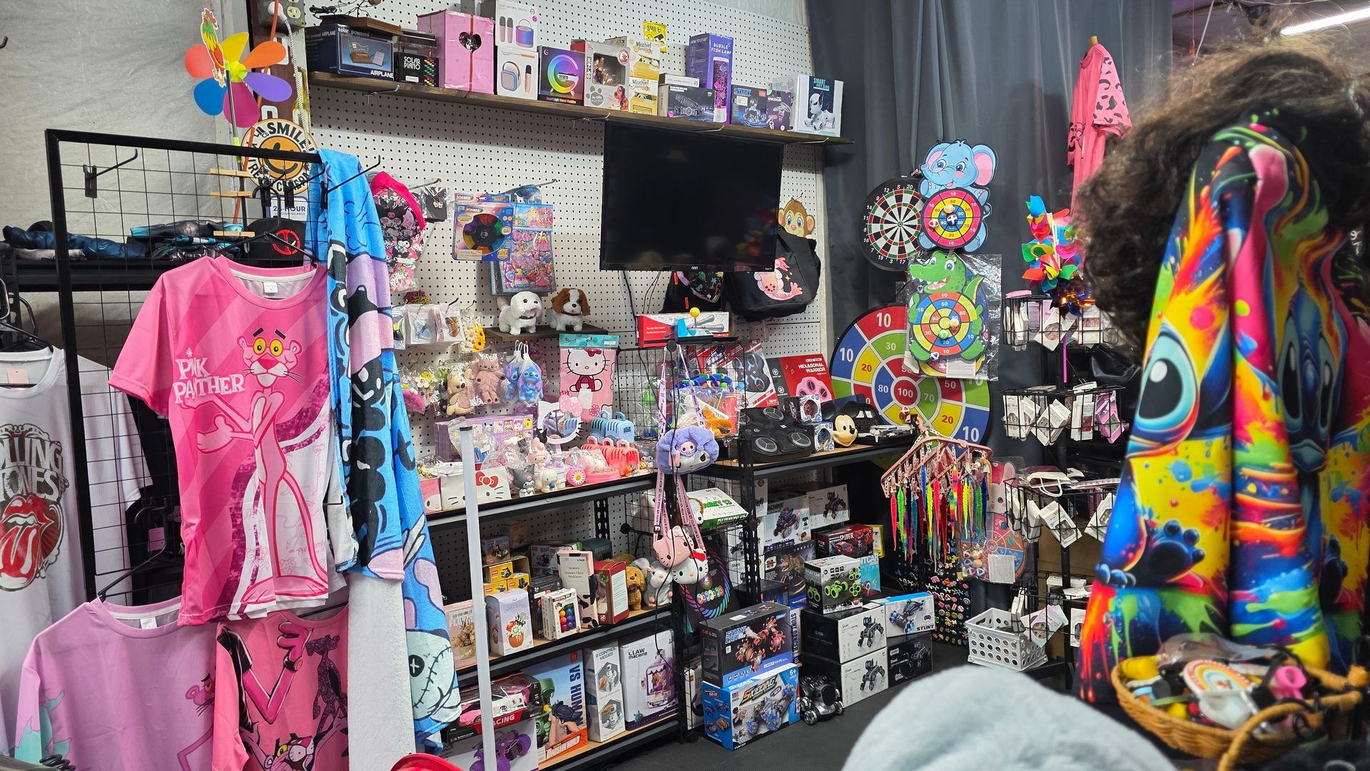 A colorful, cluttered shop display. Clothing, merchandise, and accessories on shelves and racks.
