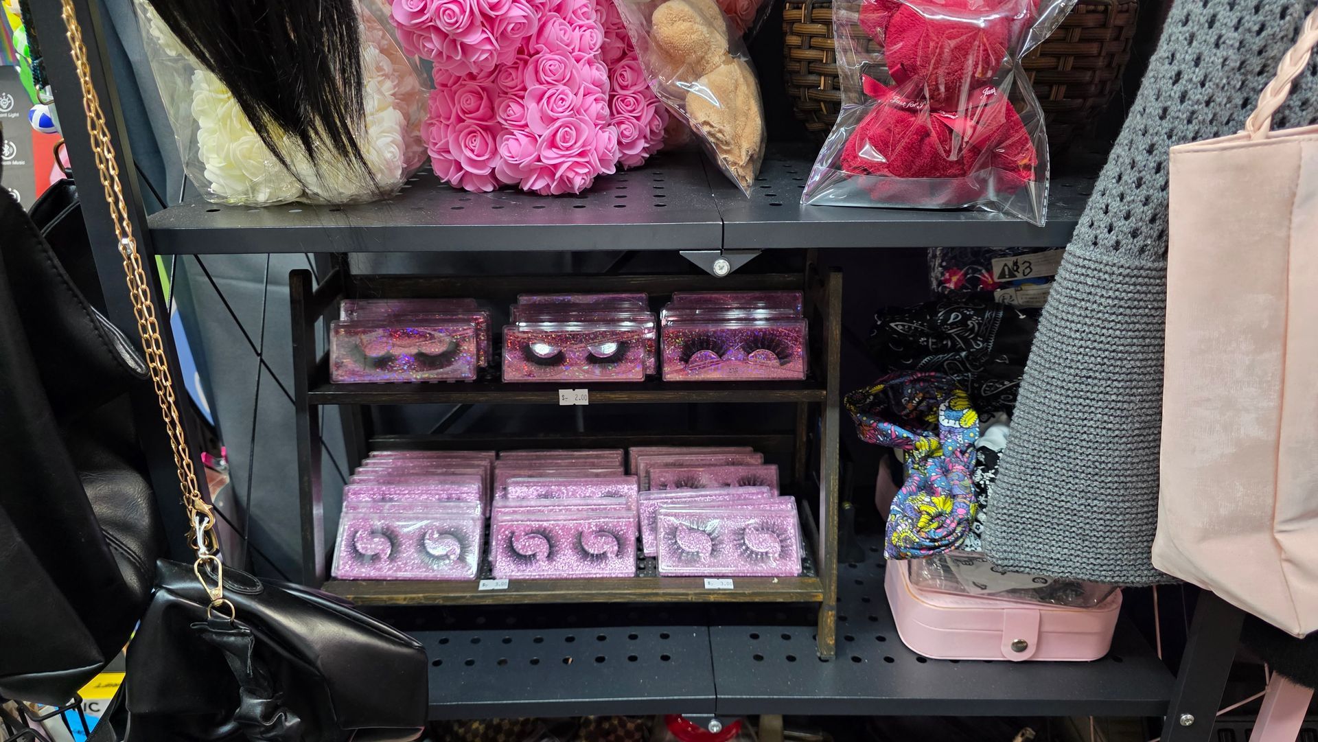 A well-lit boutique with shelves of wigs, clothing, and makeup. A central display has flowers.