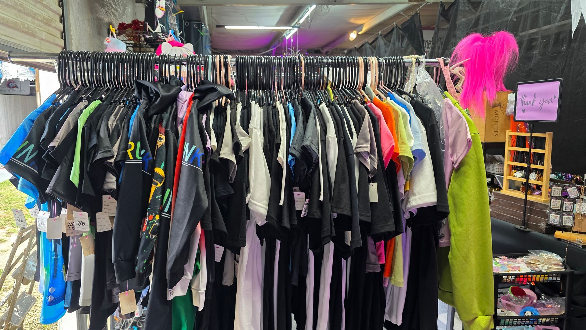 Clothes rack with black, white, and colorful shirts and hoodies on display at an outdoor market.