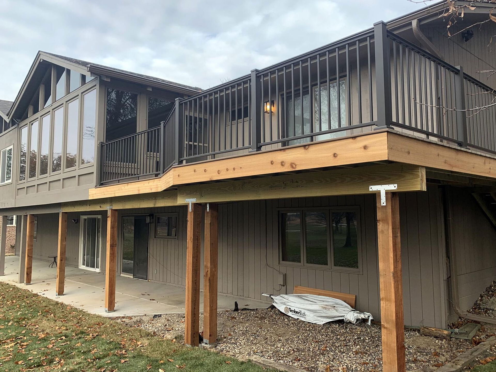 Partially renovated house with an upper deck and exposed framing under overcast skies Partially renovated house with an upper deck and exposed framing under overcast skies