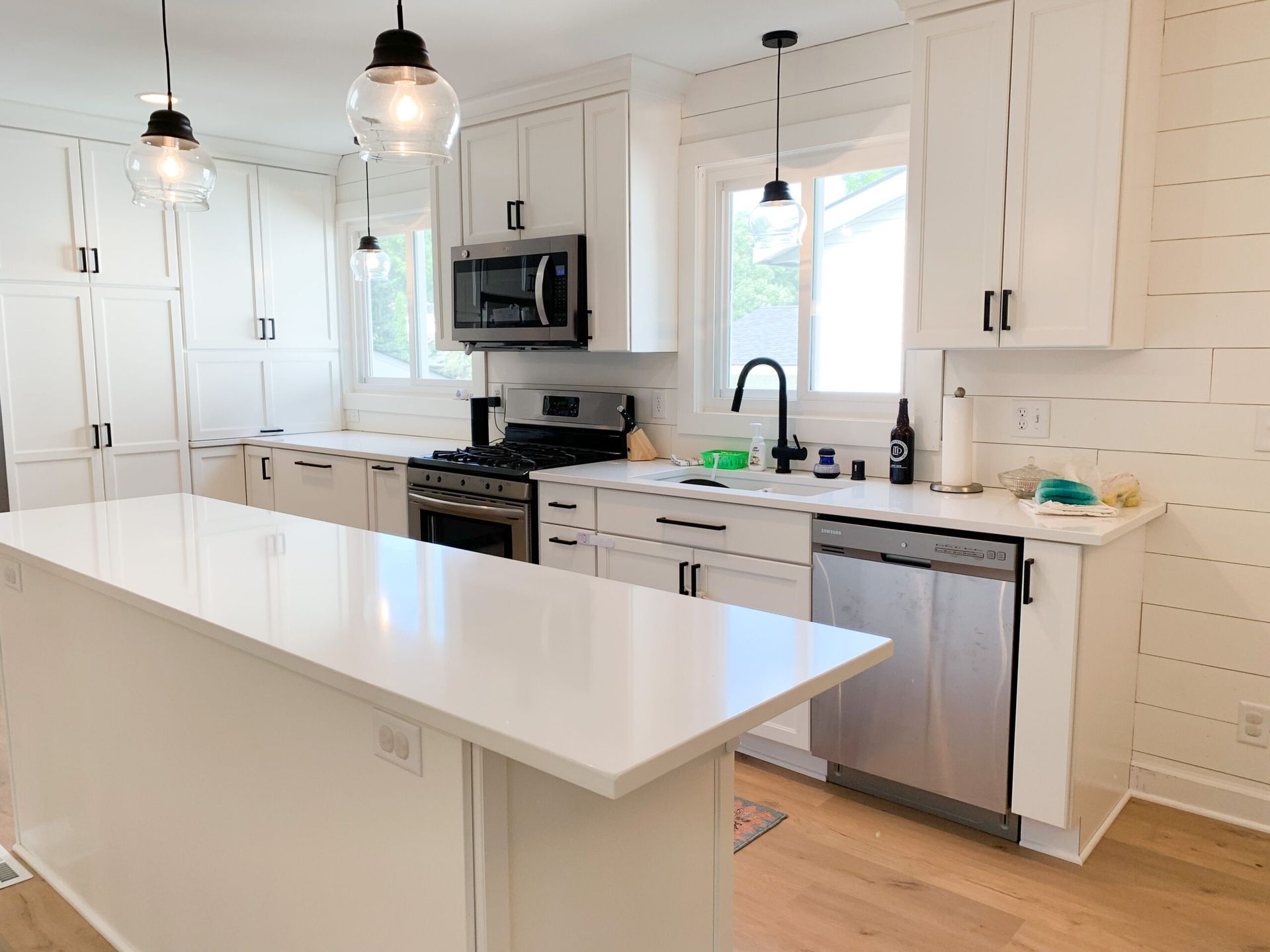 Bright white modern kitchen with island, stainless steel appliances, and pendant lights