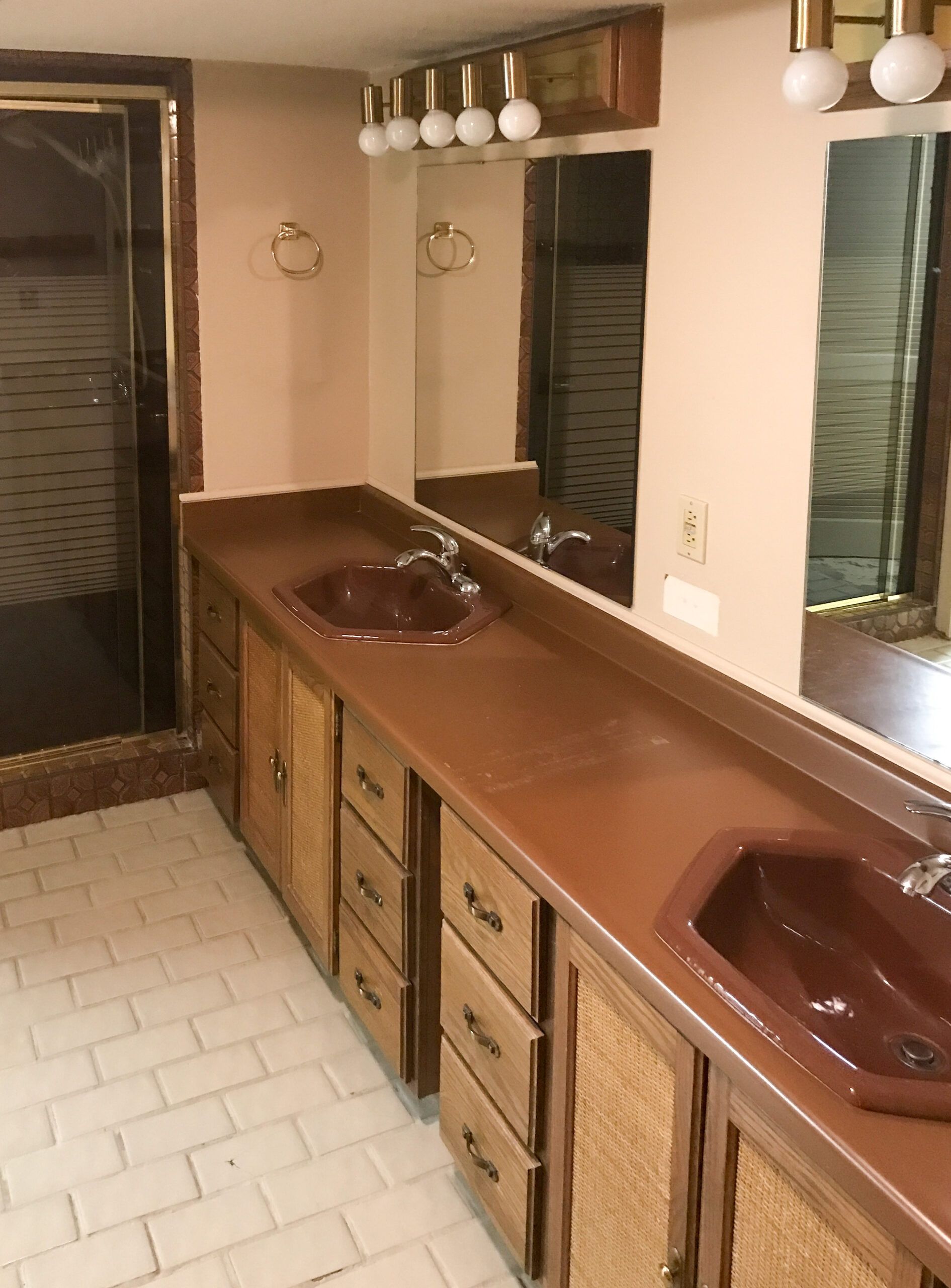 Bathroom with long wood vanity, two sinks, large mirror, and tiled floor.