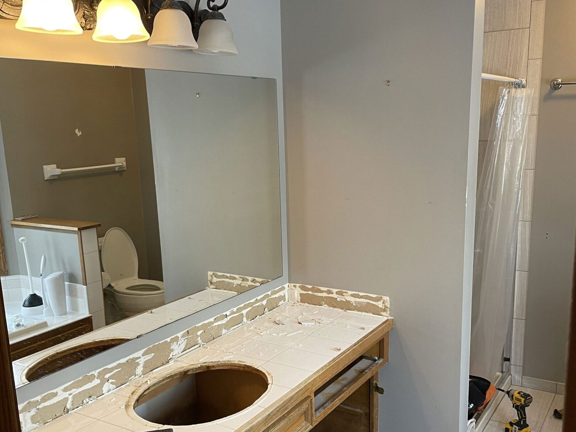 Bathroom vanity under renovation with an open sink cutout, mirror, and shower curtain in the background Bathroom vanity under renovation with an open sink cutout, mirror, and shower curtain in the background