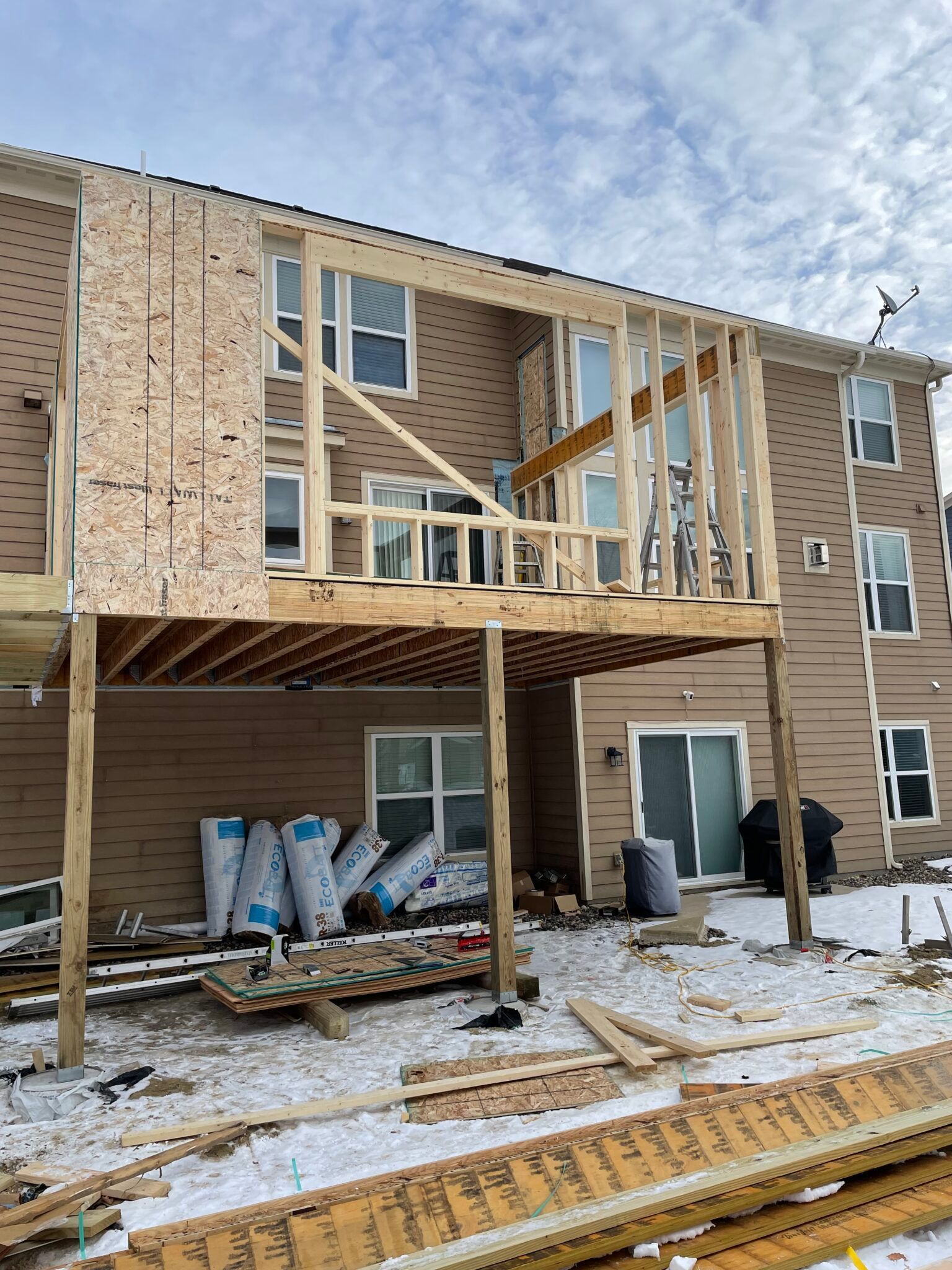 Partially built townhouse with exposed framing and snow-covered ground outside Partially built townhouse with exposed framing and snow-covered ground outside