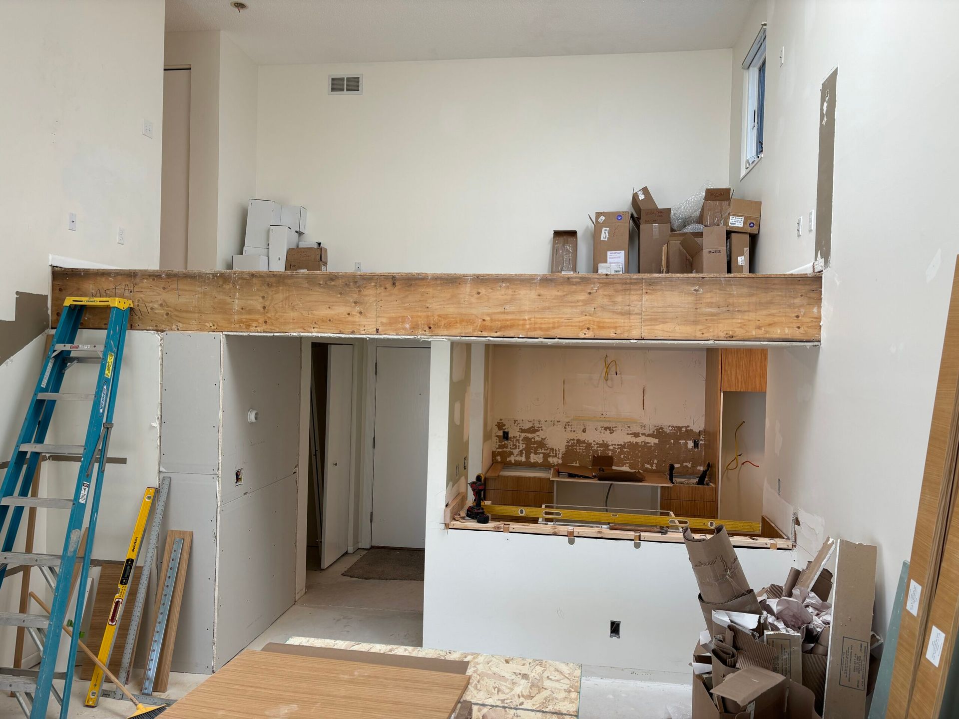 Construction area with wood loft, ladders, and unfinished walls in a white room