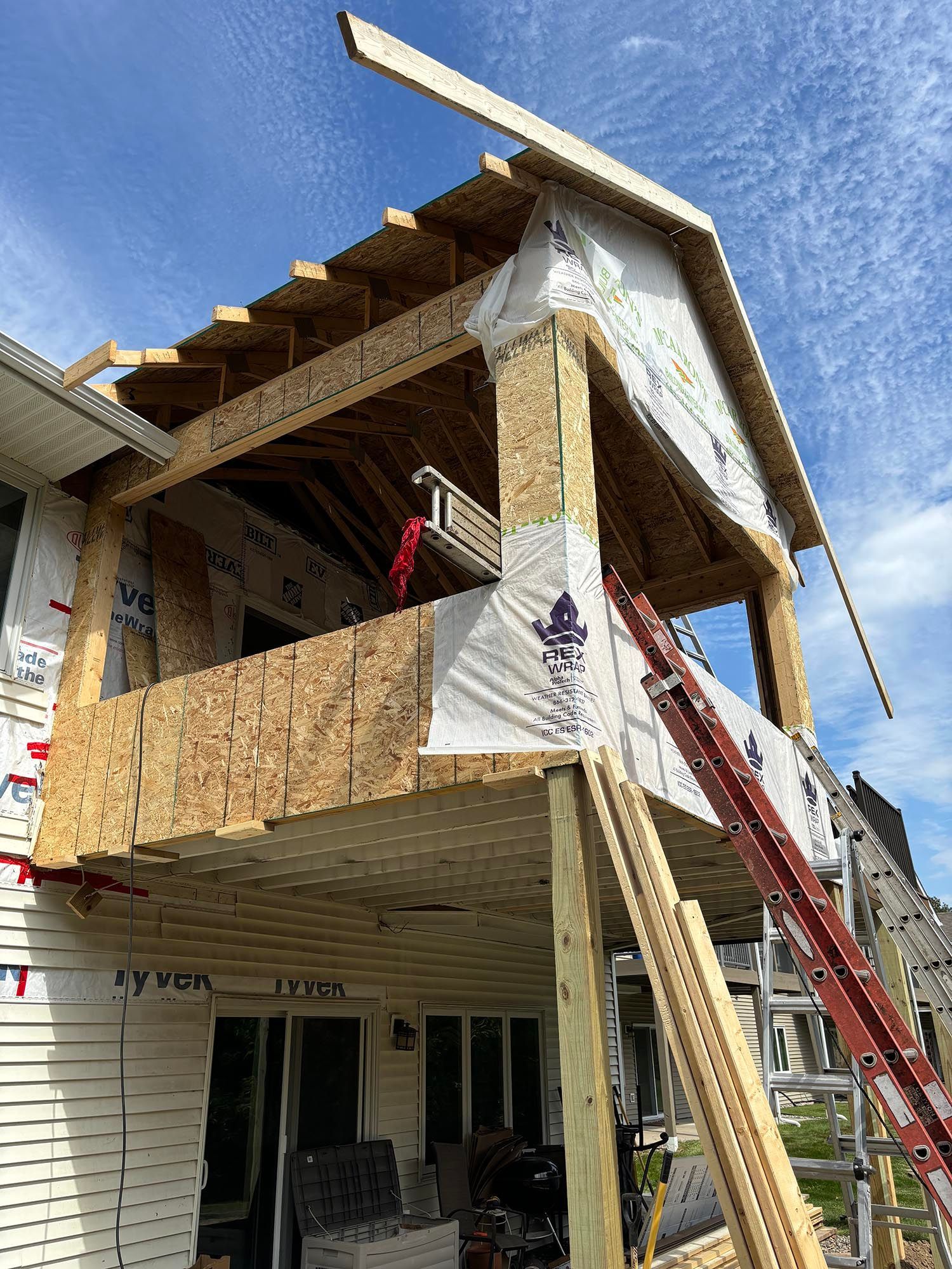 Partially built house with exposed wood framing and scaffolding under a blue sky