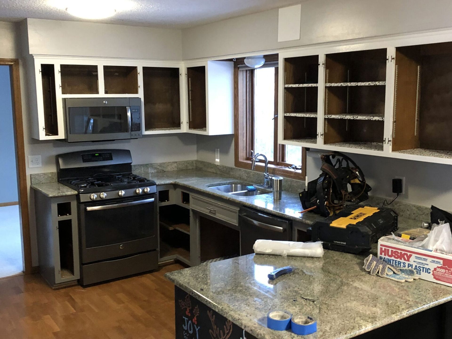 Kitchen with unfinished cabinets, black stove, granite counter, and sink near a window. Kitchen with unfinished cabinets, black stove, granite counter, and sink near a window.