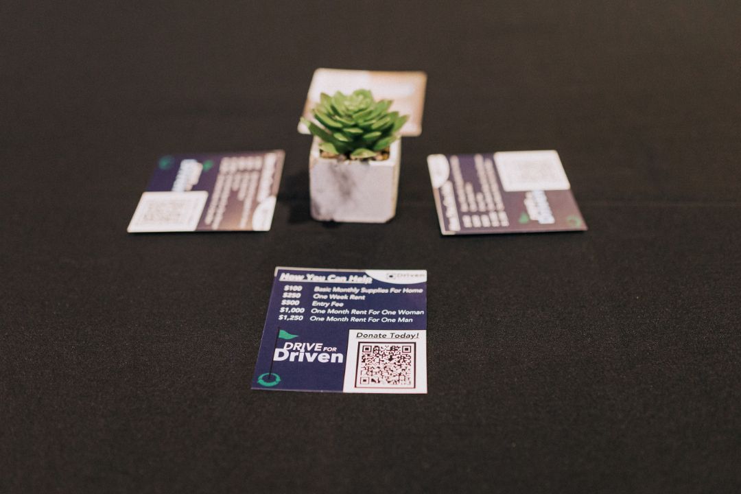 A potted plant sits next to a business card that says drive driven