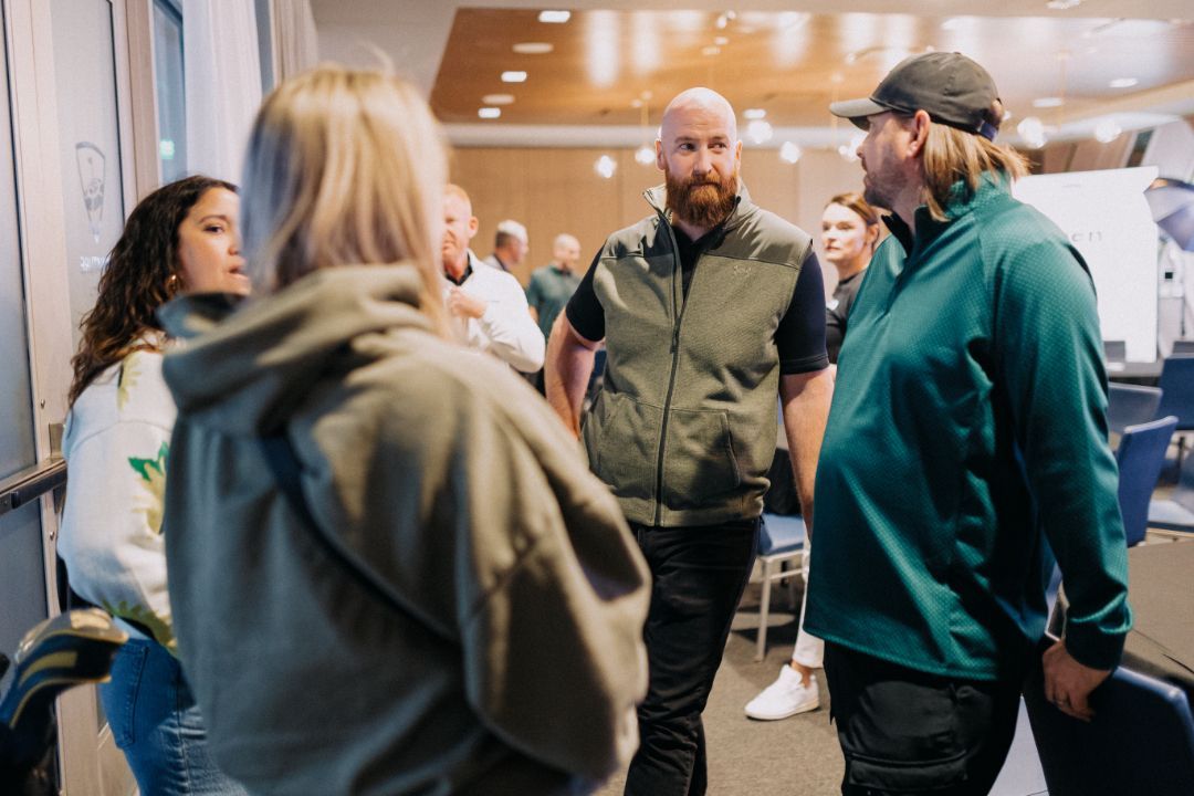 A group of people are standing in a room talking to each other.