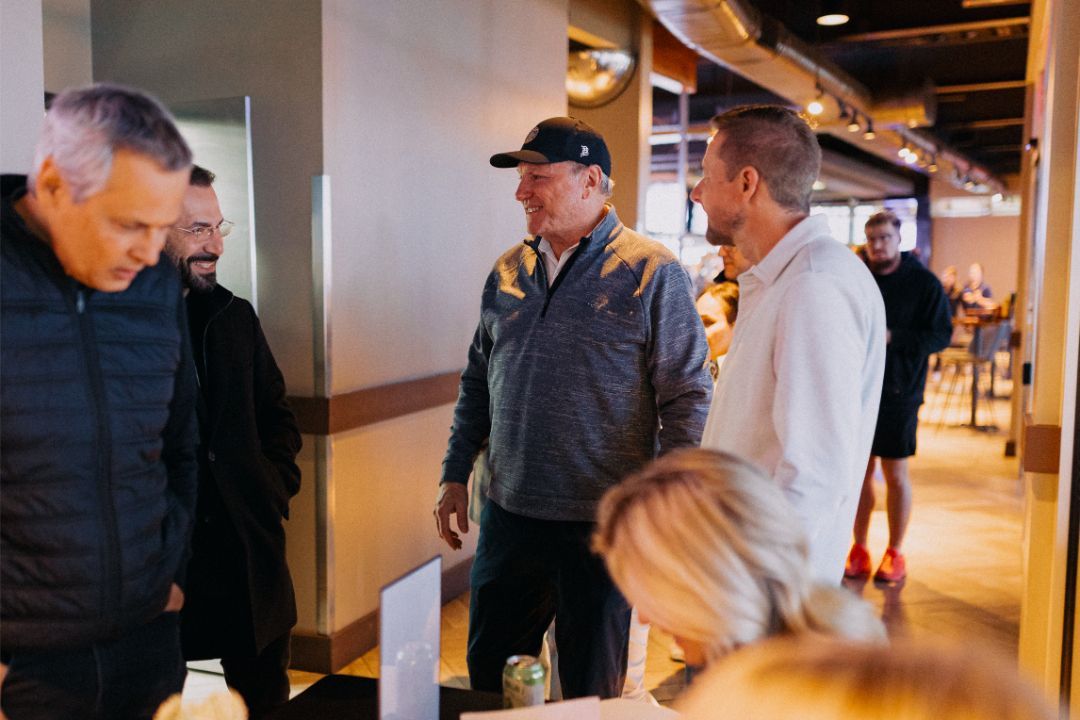 A group of men are standing in a hallway talking to each other.