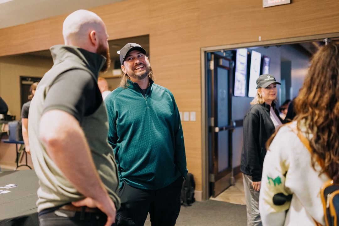 A group of people are standing in a room talking to each other.