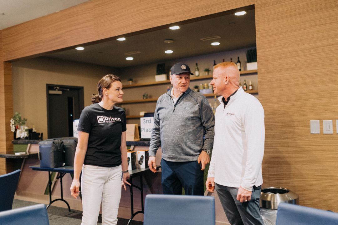 A group of people are standing in a room talking to each other.