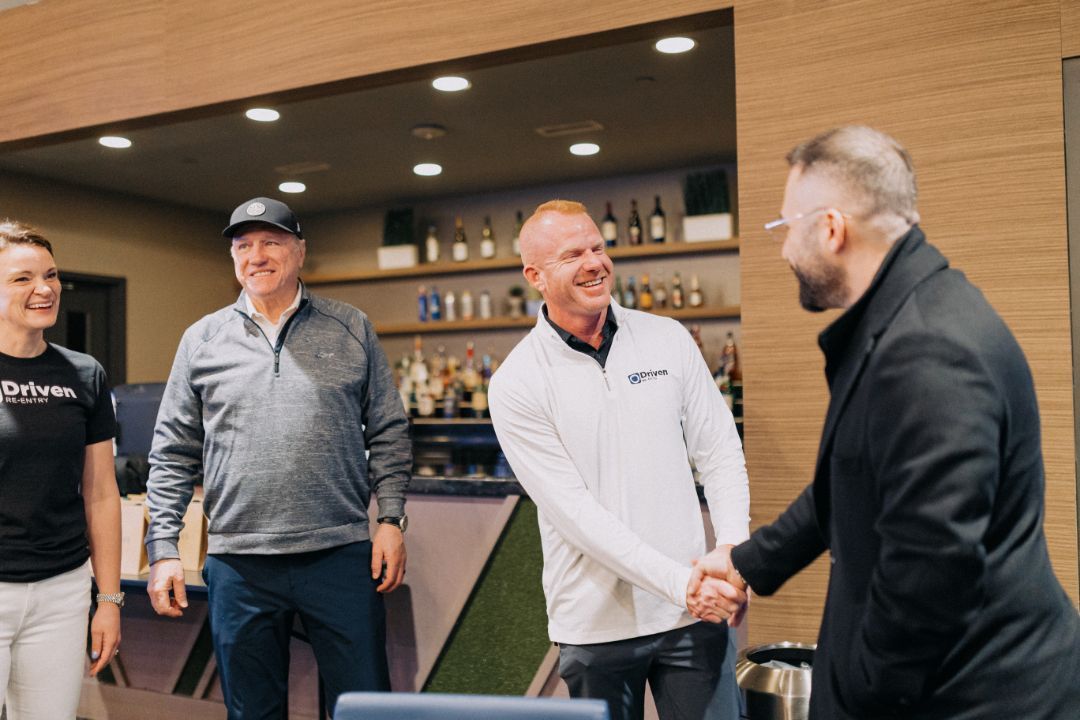 A group of men are shaking hands in a room.