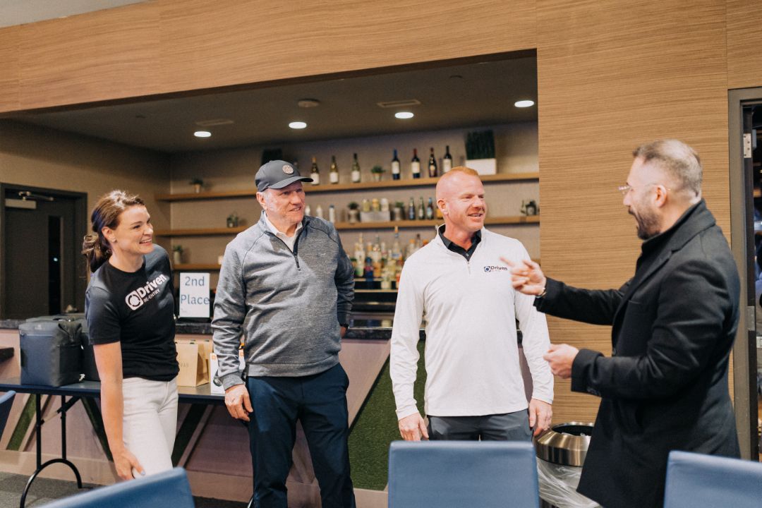 A group of people are standing in a room talking to each other.