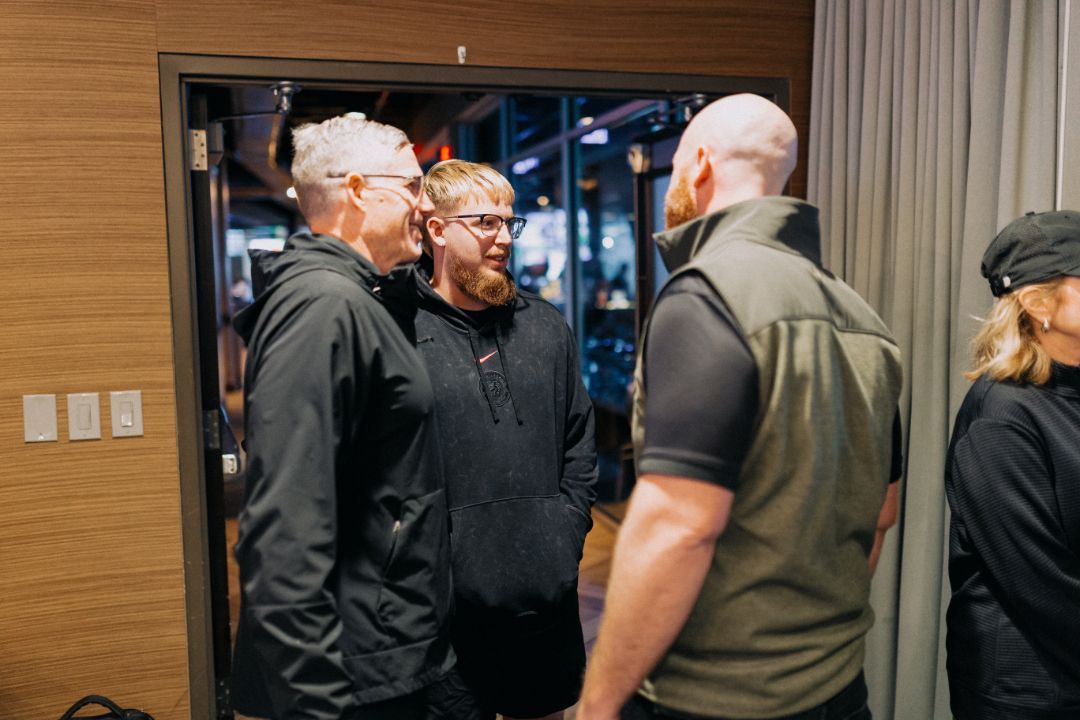 A group of people are standing in a room talking to each other.