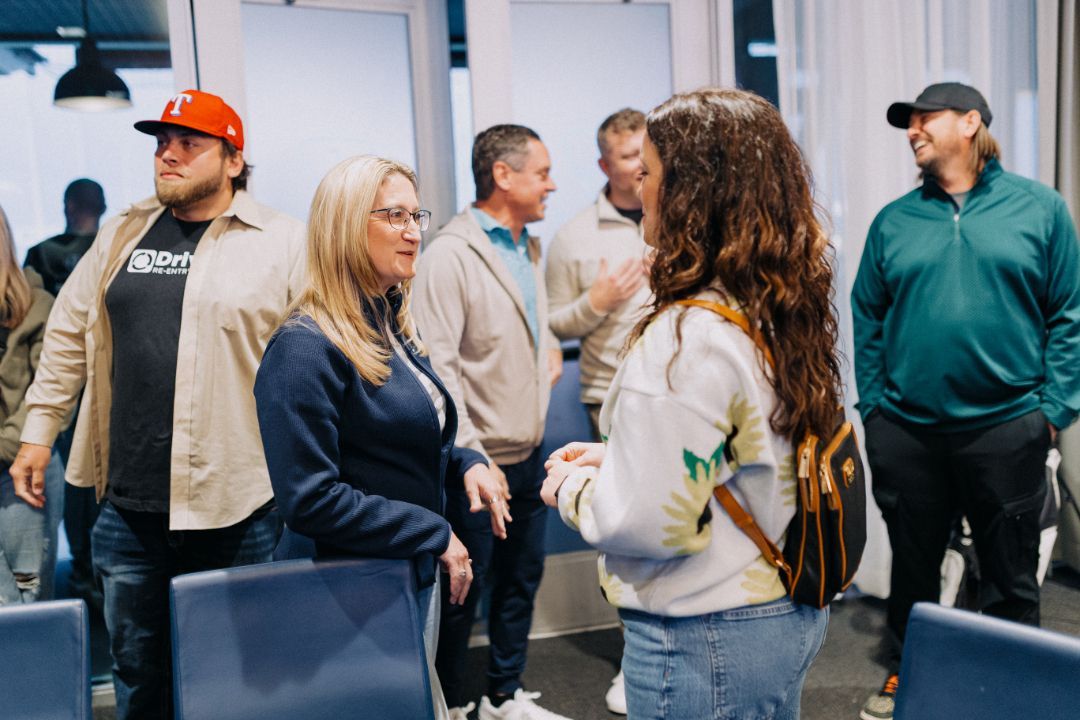 A group of people are standing in a room talking to each other.