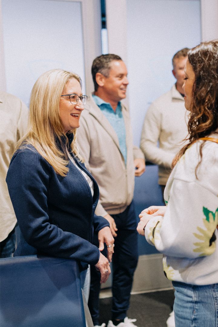 A group of people are standing in a room talking to each other.