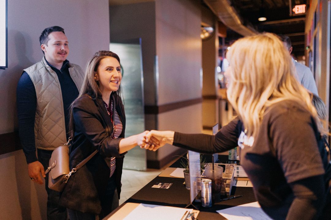 A woman is shaking hands with another woman in a room.