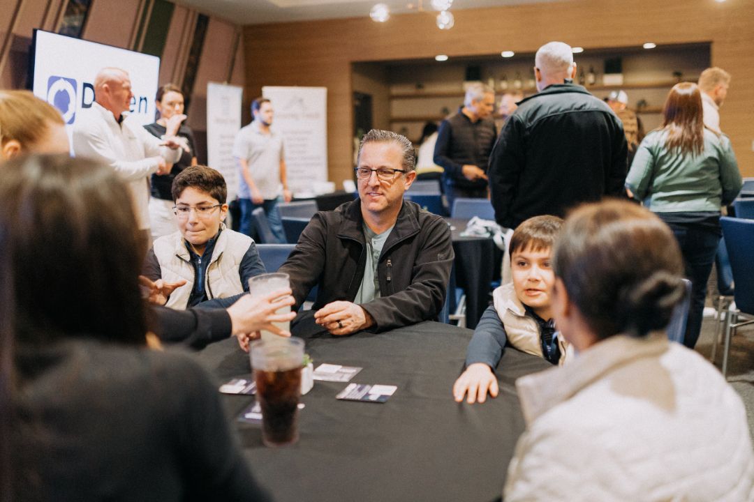 A group of people are sitting around a table talking to each other.