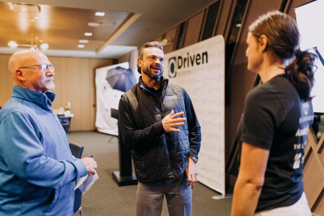 A group of people are standing in a room talking to each other.