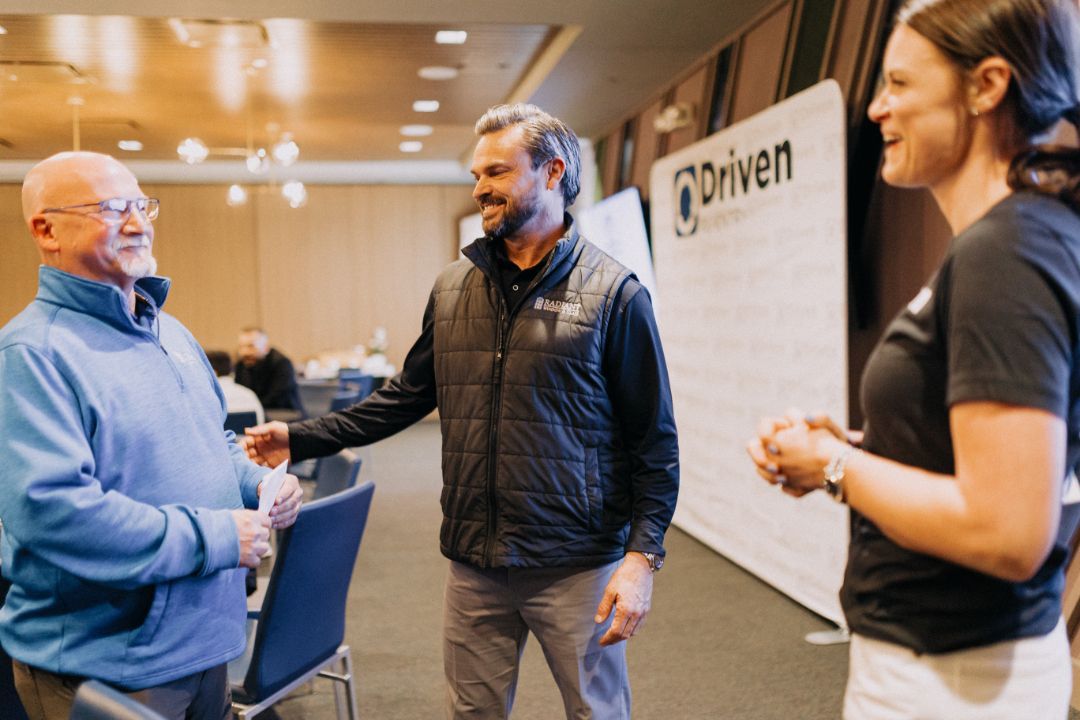 A group of people are standing in a room talking to each other.