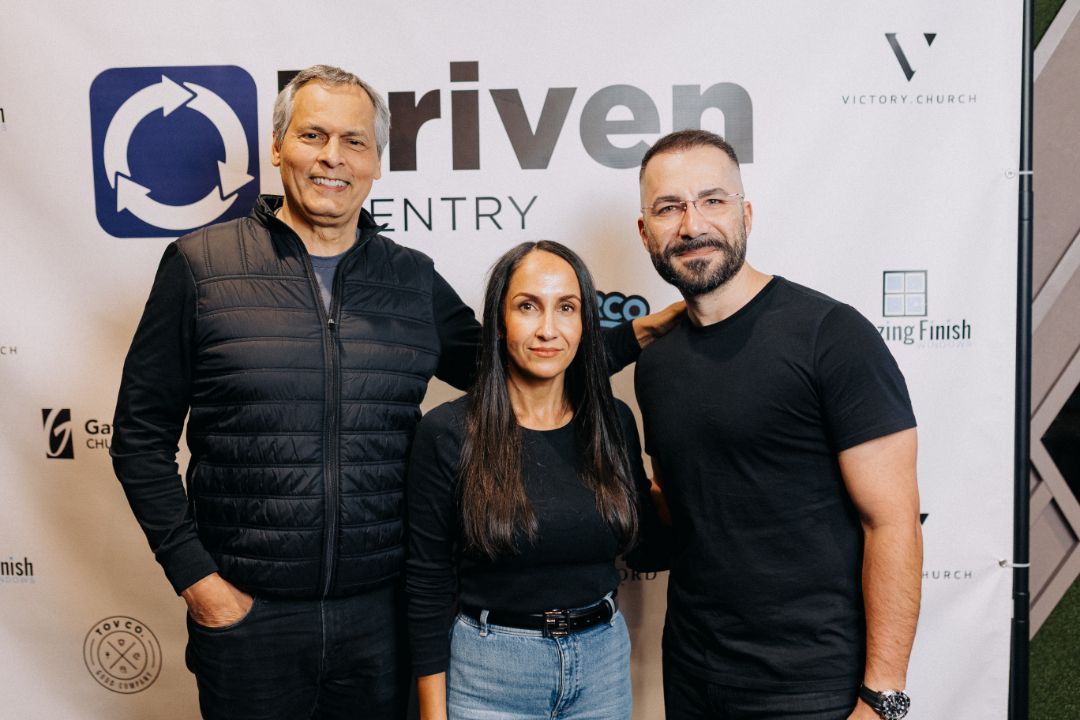 Three people are posing for a picture in front of a river entry sign.