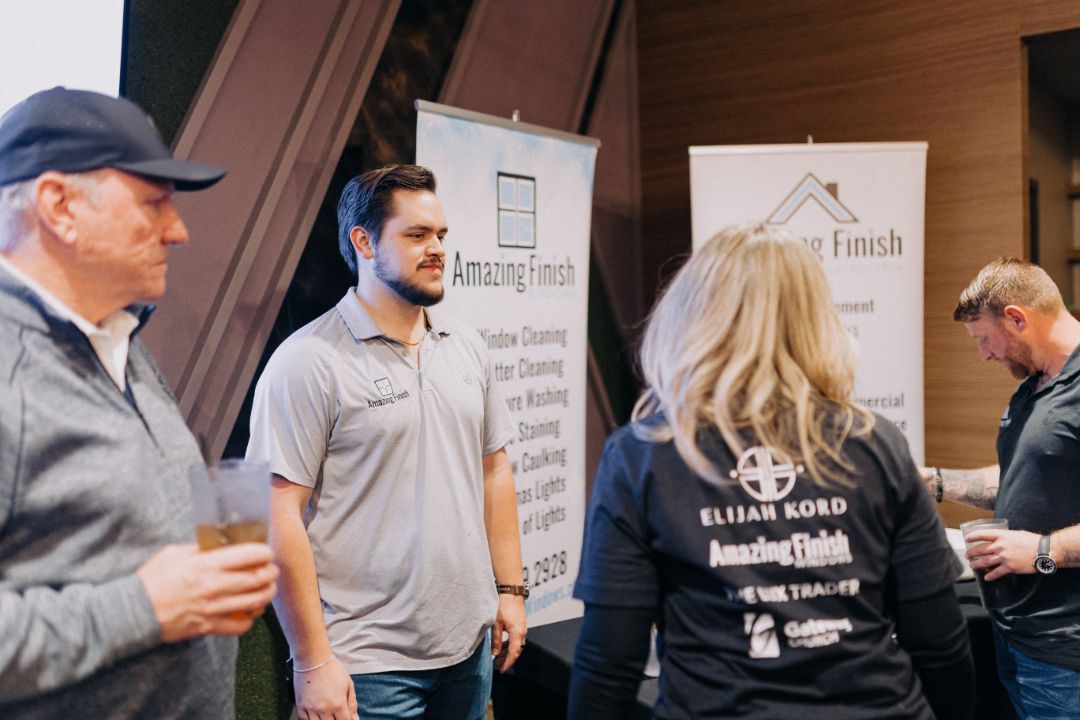 A group of people are standing in a room talking to each other.