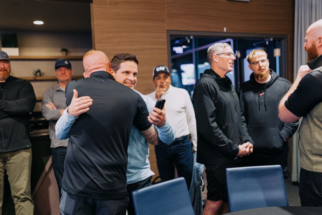 A group of men are hugging each other in a room.