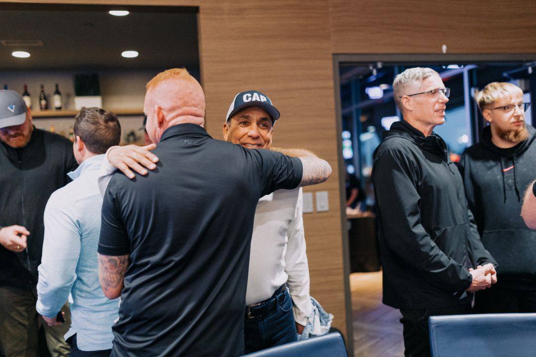 A group of men are hugging each other in a room.