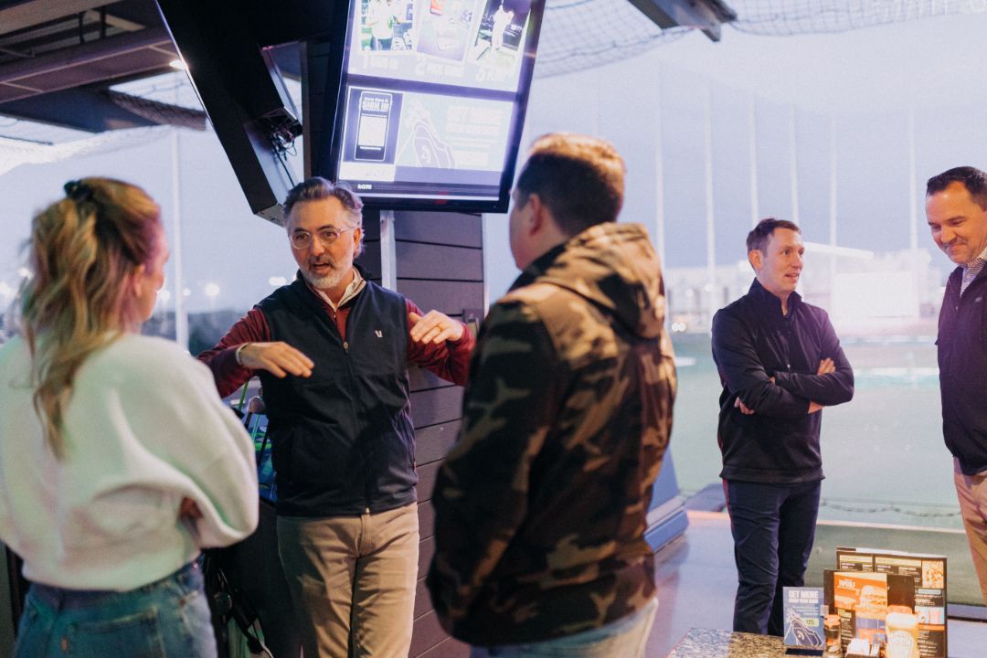 A group of people are standing in a room talking to each other.