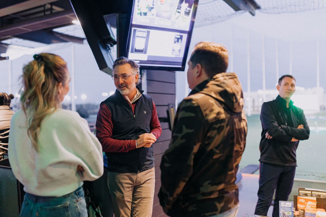A group of people are standing around talking to each other in a room.
