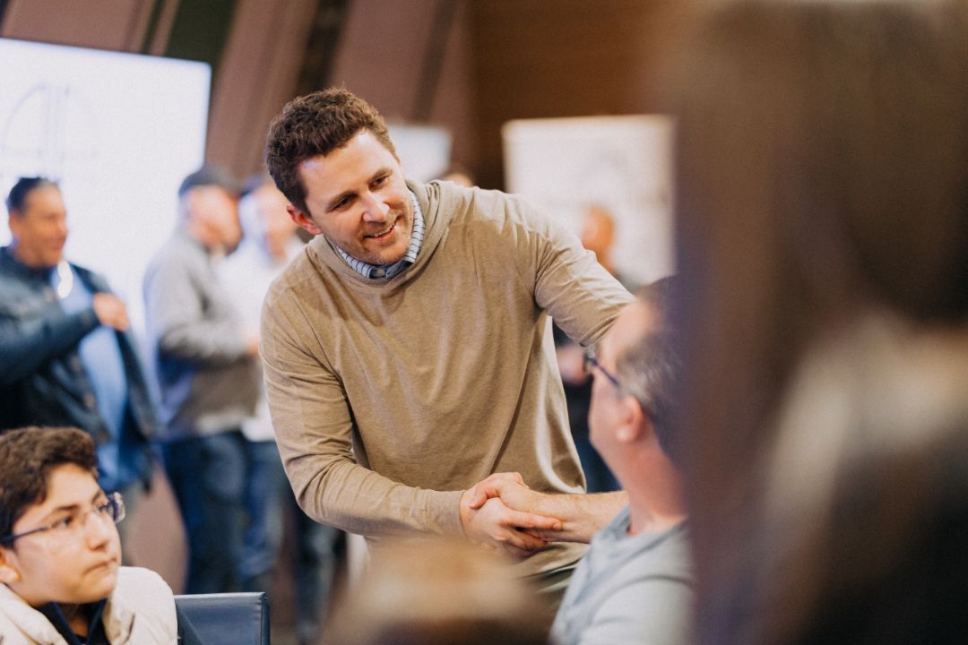 A man is shaking hands with a group of people in a room.