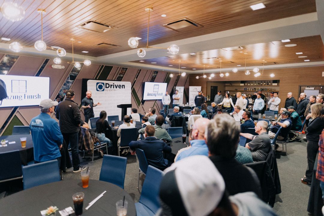 A large group of people are sitting at tables in a large room.