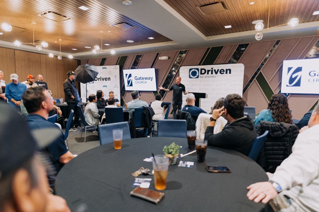 A group of people are sitting at tables in a conference room.