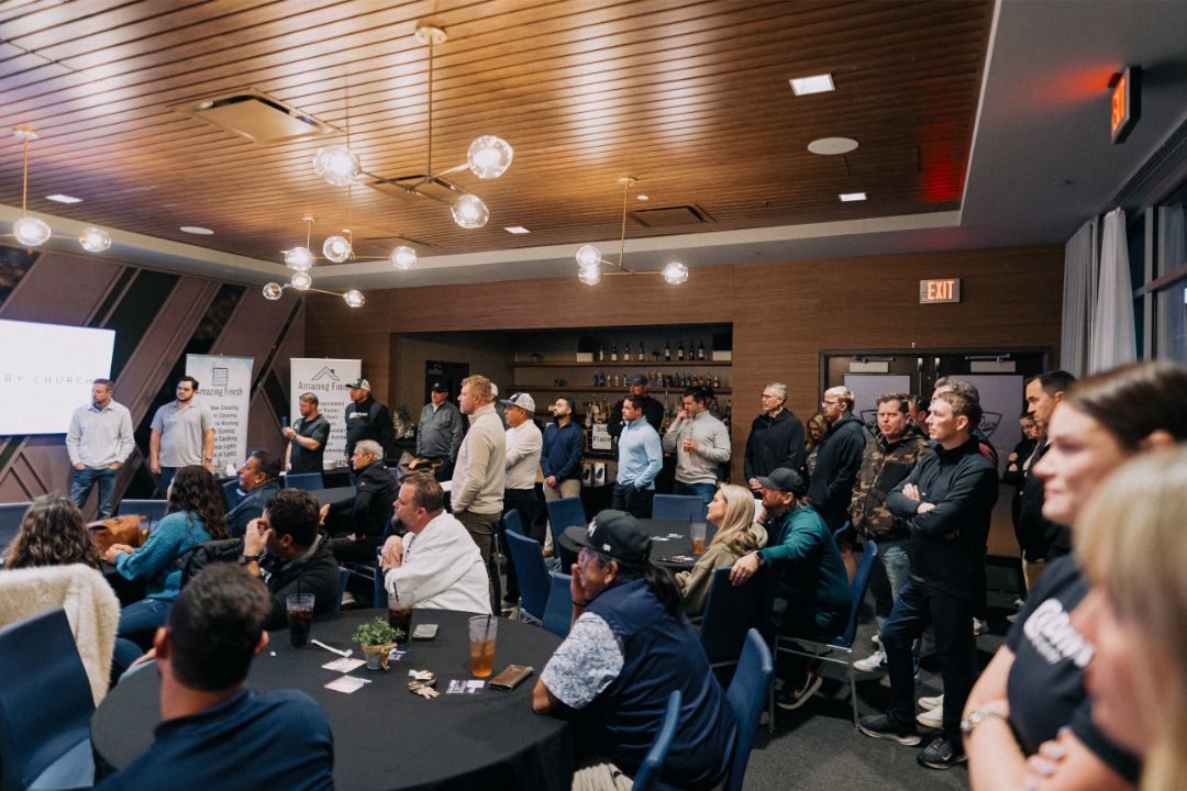 A group of people are sitting at tables in a large room.