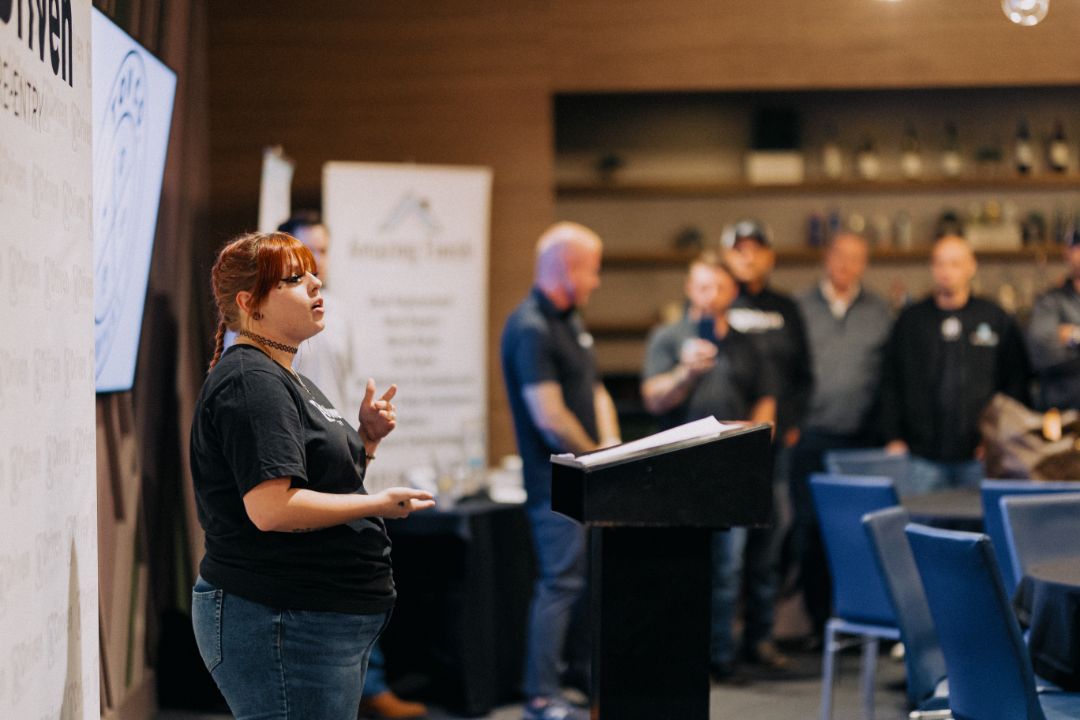 A woman is standing at a podium giving a presentation to a group of people.