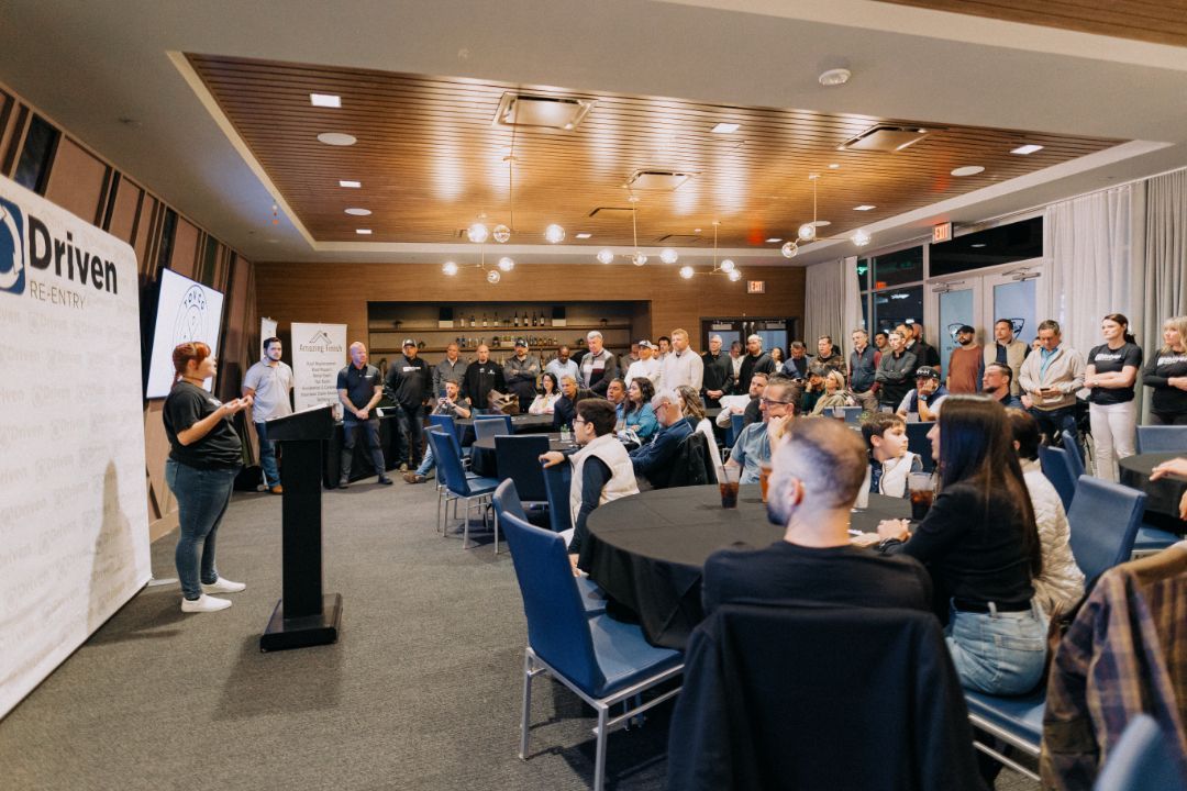 A group of people are sitting at tables in a large room.