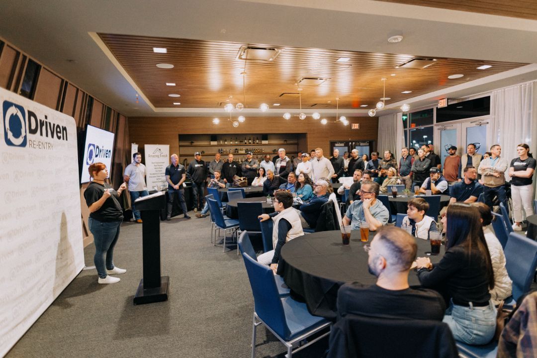 A large group of people are sitting at tables in a room.