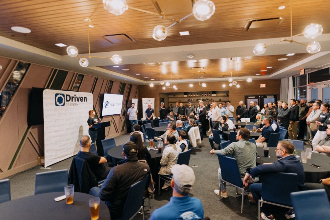 A large room filled with people sitting at tables and chairs.