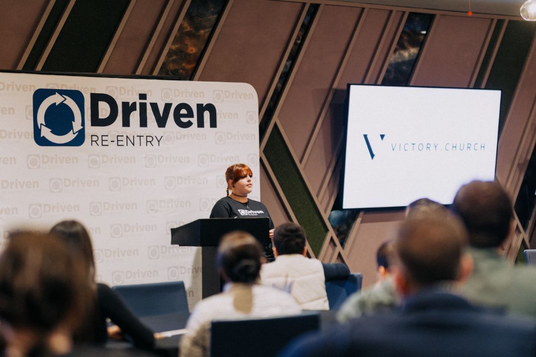 A woman is standing at a podium giving a presentation to a group of people.