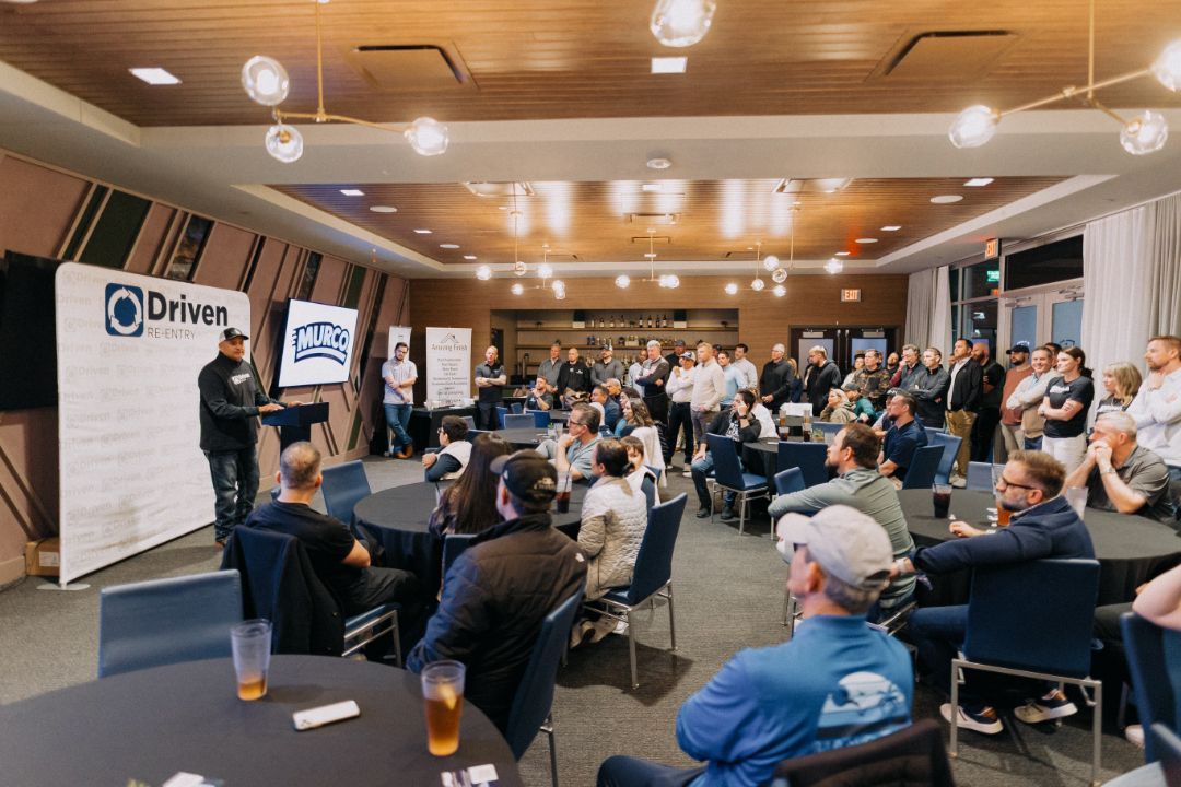 A group of people are sitting at tables in a large room.