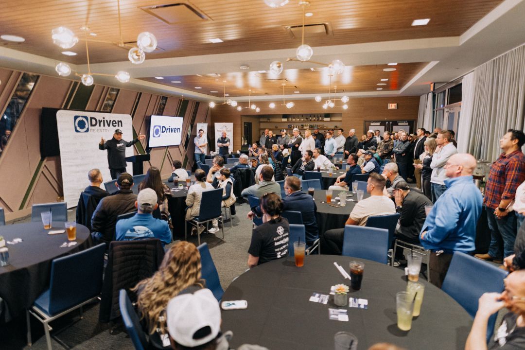 A large group of people are sitting at tables in a large room.