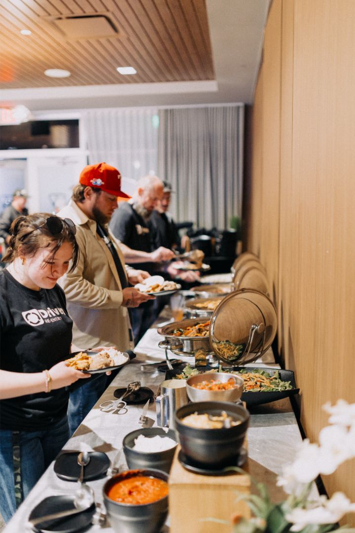 A group of people are standing at a buffet table eating food.