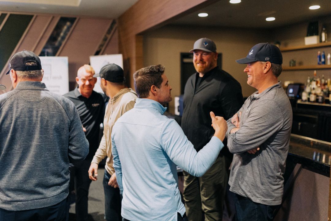A group of men are standing around talking in a room.