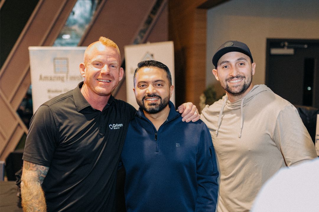 Three men are posing for a picture together in a room.